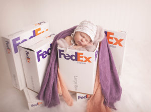 A little newborn baby in a fed ex box posed for her newborn photoshoot