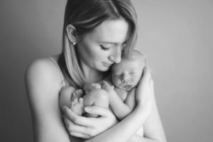 A new mom loving and snuggling her newborn baby during a newborn session with Joanna Booth Photography.
