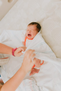 A baby crying before getting wrapped snuggly in the hospital by a doctor. Image captured by Joanna Booth Photography during a Fresh 48 session in Houston Texas.