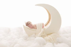 A precious baby girl sitting on a moon prop in th