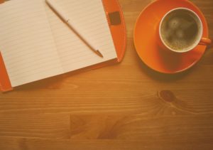 A picture of a notebook, with a pencil, and coffee.