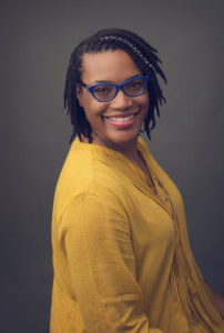 African-American woman in yellow shirt with blue glasses and dreads in professional headshot taken by Joanna Booth of Sanguine Portraiture. Joanna is located in Katy, Texas and serves the Katy and Houston, Texas areas.