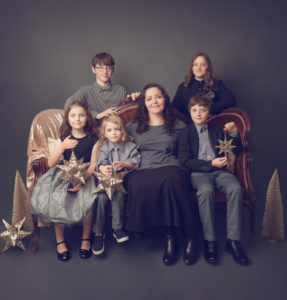 A woman sitting on a vintage victorian brown couch with her five children during a professional holiday portrait taken by Joanna Booth of Sanguine Portraiture. Joanna is located in katy Texas and serves the Houston Texas areas